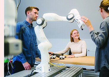 Studierende und Mitarbeitende der HTW Berlin arbeiten mit einem Roboterarm